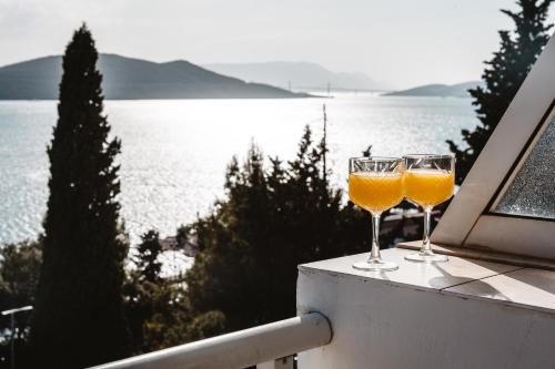 two wine glasses sitting on a balcony with a view of the water at Apartman Tulipan Neum in Neum