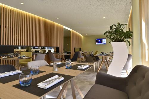 a restaurant with tables and chairs and a tv at Novotel Paris Nord Expo Aulnay in Aulnay-sous-Bois