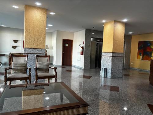 a lobby with two chairs and a glass table at Flat centro - Via Park in Campos dos Goytacazes