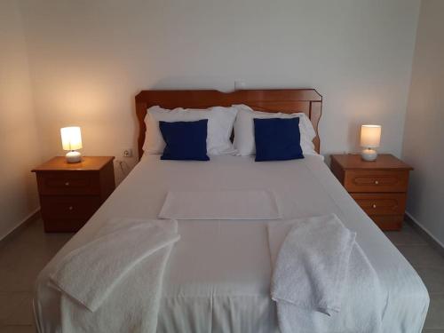 a bedroom with a large white bed with blue pillows at Le Bellevue in Mavráta