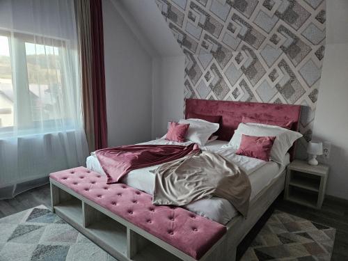 a bed with a pink headboard in a bedroom at Pensiunea Michael's House in Rupea
