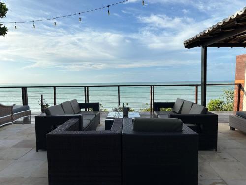 a patio with couches and a view of the ocean at Casa beira-mar centro de pipa in Pipa