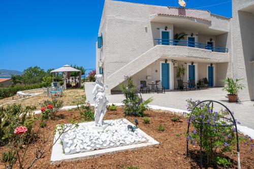 a building with a statue in front of a yard at Fiore Di Mare Studios in Lassi