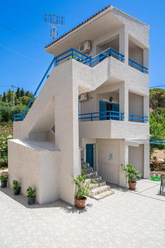 a white house with blue railing on the side of it at Fiore Di Mare Studios in Lassi