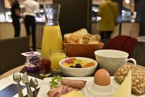 a table with a plate of breakfast food and a bottle of orange juice at Novotel Paris Nord Expo Aulnay in Aulnay-sous-Bois