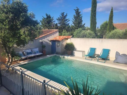 - une piscine avec deux chaises bleues à côté d'une clôture dans l'établissement Charmante maison provençale avec piscine, à Coudoux