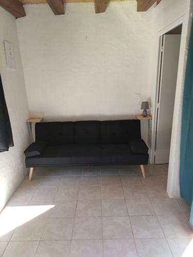 a black couch in a room with a white wall at Au Logis Du Summer in Brioude