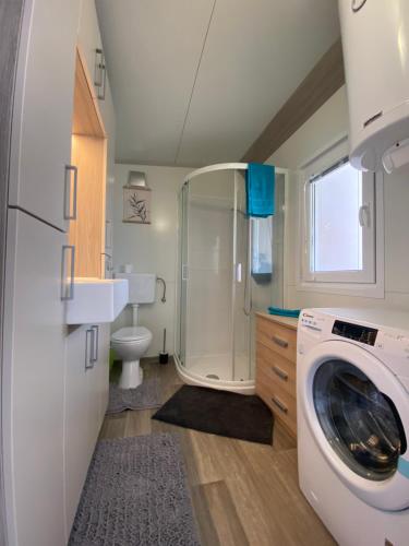 a bathroom with a shower and a washing machine at Mediterranean mobile homes - Lotty in Drage
