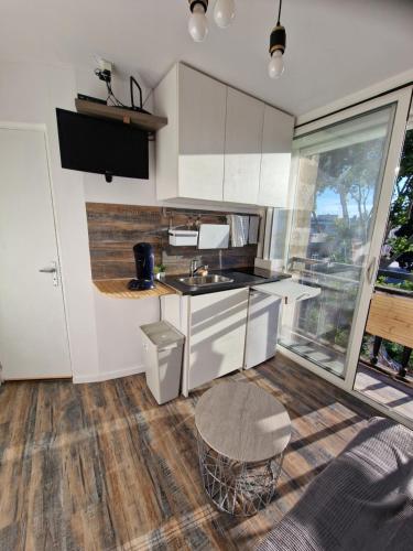 a kitchen with white cabinets and a sink and a table at Les sablettes front de Mer Tour Fernand pouillon provence plage in La Seyne-sur-Mer