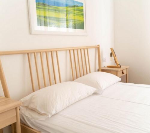 a bed with white sheets and a picture on the wall at La Cicala del Conero in Marcelli