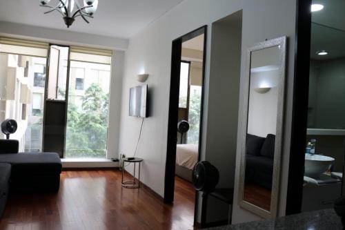 sala de estar con espejo y cama en Puerta Alameda Suites México en Ciudad de México