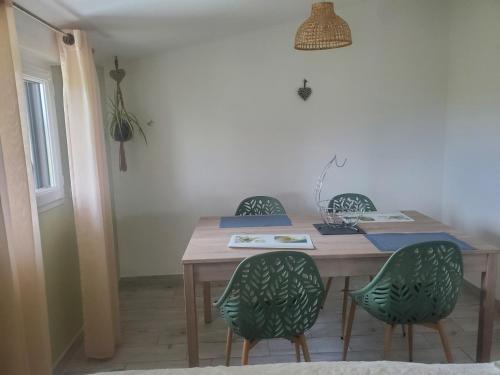 - une table à manger avec 2 chaises vertes et une table dans l'établissement Gite rural JONQUIERES 84, à Jonquières