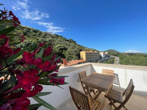 a table and chairs on a balcony with red flowers at Villa Il Guardingo in Rio nellʼElba