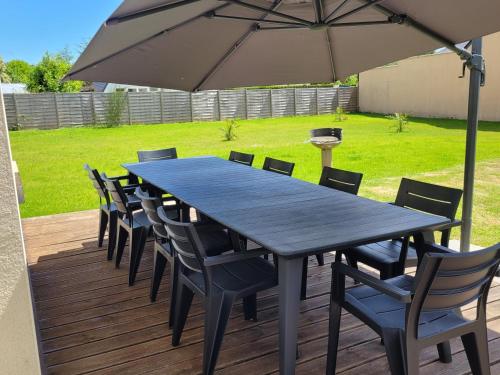 a black table and chairs with an umbrella on a deck at Kernay, grande maison familiale pour 10 personnes in Lannion