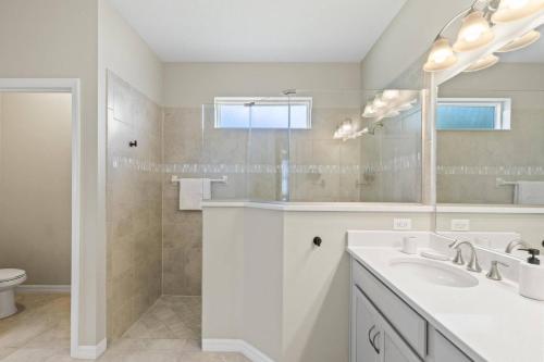 a white bathroom with a sink and a mirror at Salty Reef Pool Home | Palm Coast in Palm Coast