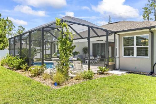 a home with a pool and a glass house at Salty Reef Pool Home | Palm Coast in Palm Coast