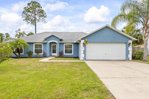 una casa blu con un garage bianco di Sandpiper Path | Palm Coast a Flagler Beach