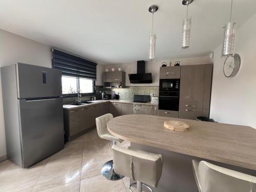 a kitchen with a table with chairs and a refrigerator at La Villa des Cistes au calme vue Étangs in Narbonne