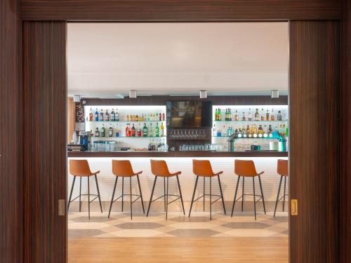 a bar with orange bar stools in a room at Holiday Inn Toulouse Airport by IHG in Blagnac