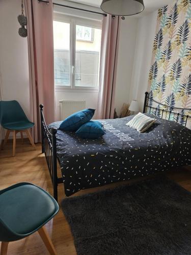 a bedroom with a bed with blue pillows and a window at Les Bulles au Féminin in Chigny-les-Roses