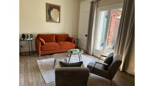 a living room with an orange couch and chairs at La maison du tripot in Honfleur