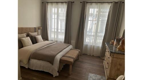 a bedroom with a bed and two windows at La maison du tripot in Honfleur