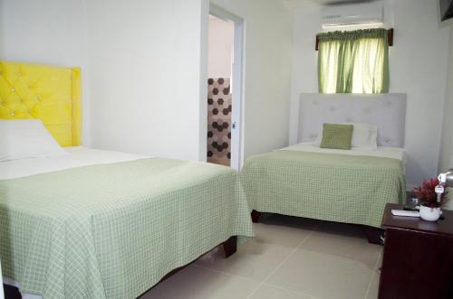 a bedroom with two beds with green and white sheets at Hotel las Nina in Paraíso