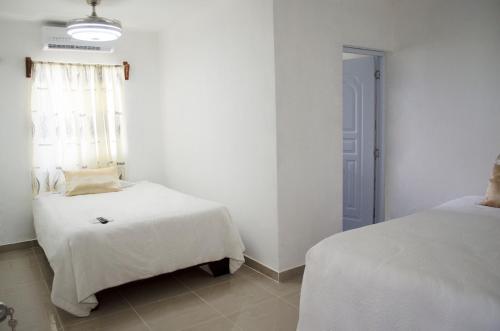 a white room with two beds and a window at Hotel las Nina in Paraíso