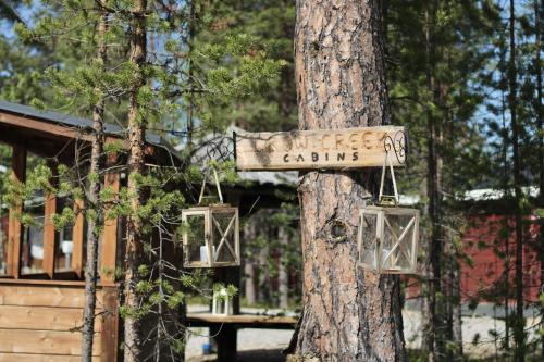 a sign on a tree in front of a cabin at Crow Creek Cabins in Inari