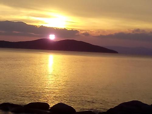 a sunset over the water with a mountain in the background at Porto Kalliali in Ouranoupoli