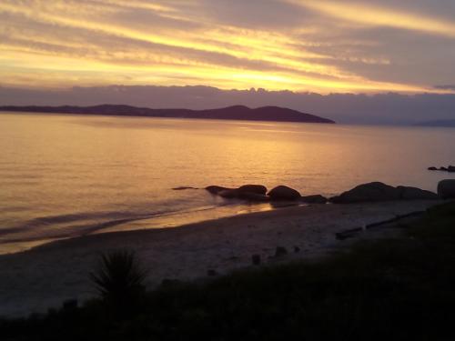 a sunset on a beach with rocks in the water at Porto Kalliali in Ouranoupoli
