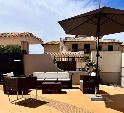 a patio with chairs and an umbrella in front of a house at Appartamento Felice in Milo