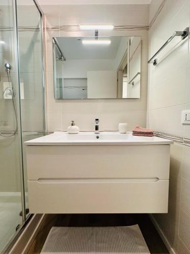 a white bathroom with a sink and a mirror at Appartamento Felice in Milo