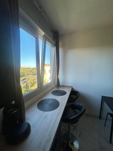 une pièce avec une table et deux chaises et une fenêtre dans l'établissement Deniphasco, au Cap d'Agde