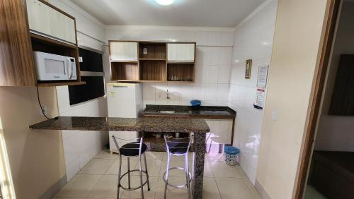 a small kitchen with a counter and two stools at Lacqua diRoma 1 - Apartamentos JN in Caldas Novas