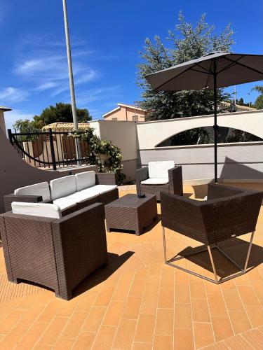 a patio with tables and chairs and an umbrella at Appartamento Felice in Milo