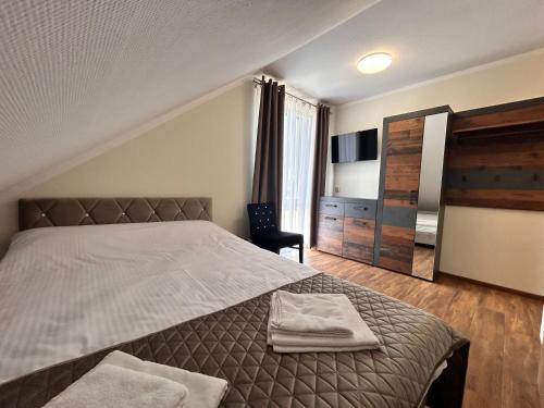 una camera da letto con un letto con due asciugamani sopra di BIAŁY DOM - Pokoje do wynajęcia a Rozogi