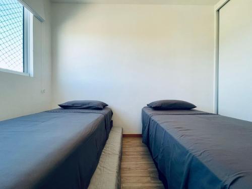 two beds sitting next to each other in a room at Apto 6º andar, 200m praia, 15min Beto Carrero, 2 quartos, sacada com churrasqueira in Piçarras