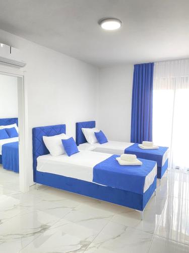a bedroom with two beds and blue curtains at Nejla Apartmani Stoj in Ulcinj