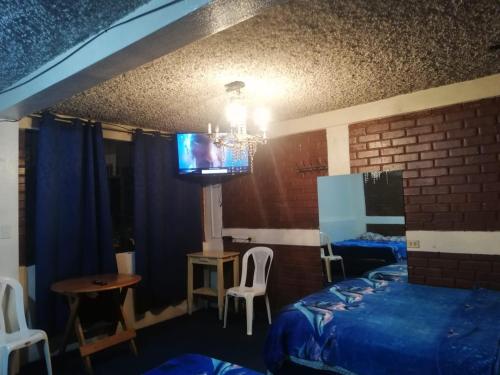 グアテマラシティにあるHotel el Mesón, Guatemalaのベッドと壁にテレビが掛かった寝室