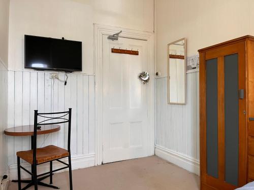 a room with a tv and a chair and a door at Golden Cross Hotel in Waihi