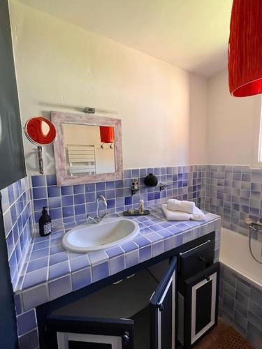 La salle de bains est pourvue de carrelage bleu, d'un lavabo et d'un miroir. dans l'établissement Grand Mas avec piscine sur Ramatuelle-Saint-Tropez, à Ramatuelle