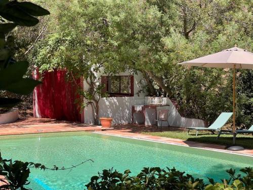 - une piscine avec un parasol, une table et une chaise dans l'établissement Grand Mas avec piscine sur Ramatuelle-Saint-Tropez, à Ramatuelle