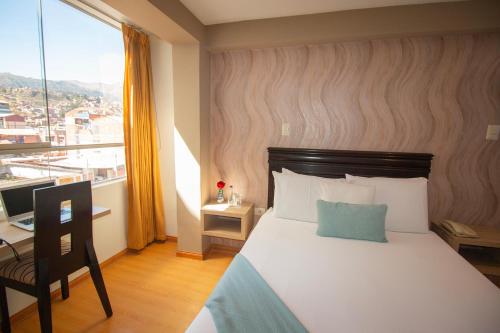 a bedroom with a bed and a desk and a window at Inti Tampu Inn in Cusco