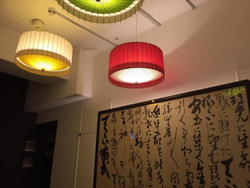 two lights hanging from the ceiling with writing on the wall at R&Run Kyoto Serviced Apartment & Suites in Kyoto