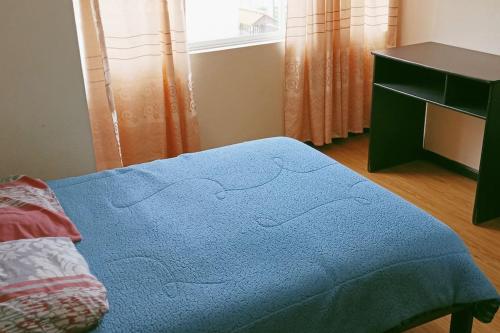 a bedroom with a blue blanket on a bed at Departamento El Rosal 2 in Cuenca