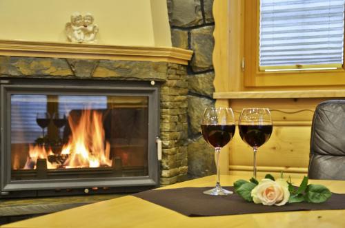 two glasses of wine on a table in front of a fireplace at Luxdomki in Szczawnica