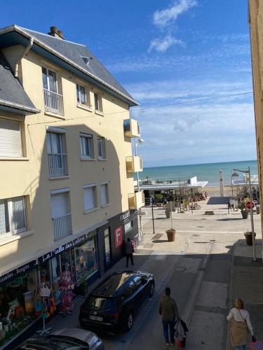 un immeuble avec une voiture garée à côté de la plage dans l'établissement Appartement duplex Luc sur Mer, en face de la plage, à Luc-sur-Mer