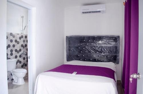 a small room with a bed and a toilet at Hotel las Nina in Paraíso