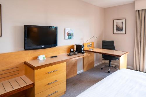 a hotel room with a desk and a tv at Holiday Inn London Brentford Lock by IHG in Brentford